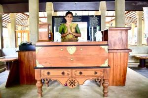 a woman is standing behind a wooden table at Nil Diya Mankada Safari Lodge in Udawalawe