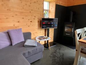 a living room with a couch and a flat screen tv at Hyggehytten auf Bornholm in Østermarie