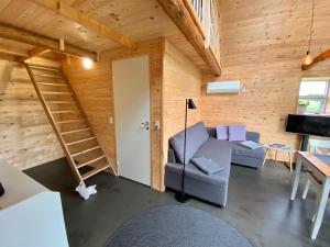 uma sala de estar com um sofá cinzento e uma escada em Hyggehytten auf Bornholm em Østermarie