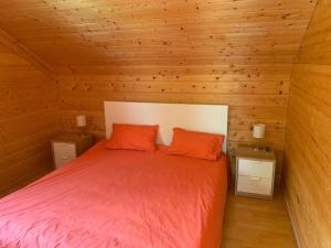 a bed in a wooden room with two orange pillows at Chalet de la Rua, Risoul Village in Risoul