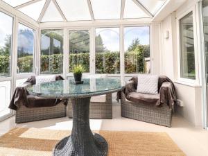a conservatory with a glass table and chairs at Palm Court in Carnforth