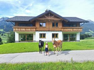 a woman standing in front of a house with two horses at Appartementhaus zum Moserlhof in Ennsling