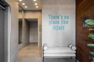 une chaise dans un couloir avec un panneau indiquant qu'il n'y a pas d'endroit comme chez soi dans l'établissement Mate GEORGE - By HOMY, à Tel Aviv