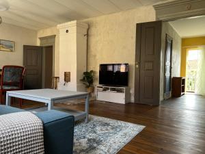 a living room with a table and a tv at Rooms in the center of Ystad in Ystad