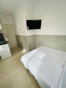 1 dormitorio con 1 cama blanca y TV de pantalla plana en Estudio La Perla, en Ceuta