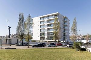 a large white building with cars parked in a parking lot at DOURO VIEWS Luxury Design Beach Apartment in Vila Nova de Gaia