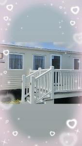 a house with a white porch and a white fence at Private Caravan Camber Sands in Camber