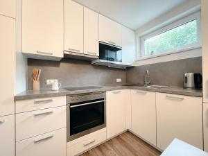 a white kitchen with white cabinets and a window at Rooms 73 - Helga Bartos in Pörtschach am Wörthersee