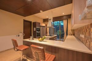 a kitchen with a counter and two chairs in it at Misty Villa by Tropicana Stays in Lonavala