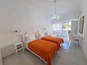 een witte slaapkamer met een bed met een oranje deken bij NN Rooms and Suites near Athens Airport in Spáta