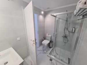 een witte badkamer met een douche en een toilet bij NN Rooms and Suites near Athens Airport in Spáta