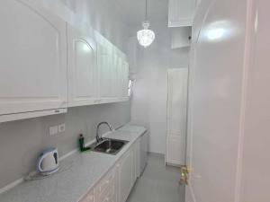 uma cozinha branca com um lavatório e armários brancos em NN Rooms and Suites near Athens Airport em Spata
