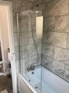 een badkamer met een douche en een bad met een glazen deur bij Trent Bridge house in Nottingham