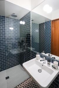 een badkamer met een wastafel en een douche met blauwe tegels bij HM - Almada City Stay in Porto