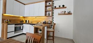 a kitchen with white cabinets and a table and chairs at Value Living Apartment in Ferizaj