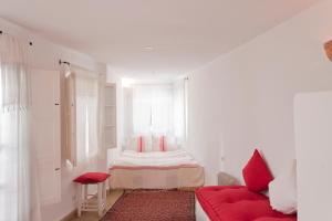 Habitación blanca con sofá rojo y ventana en La Casa Del Mar en Essaouira