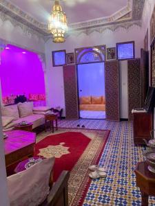 una sala de estar con iluminación púrpura y una habitación con sofá en Riad Sibari en Meknès