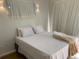 ein Schlafzimmer mit einem weißen Bett mit einer Decke darauf in der Unterkunft Luz da Lua Beach House São Miguel do Gostoso in São Miguel do Gostoso