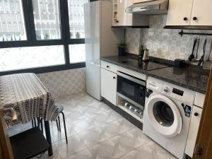 a kitchen with a washing machine and a table at Espectacular piso en la playa in Gijón