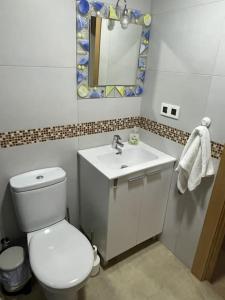 a bathroom with a white toilet and a sink at Espectacular piso en la playa in Gijón