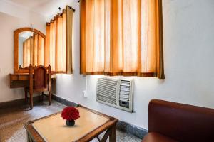Una habitación con una mesa con un jarrón de flores. en SPOT ON 93332 Hotel Maharaja, en Mysore