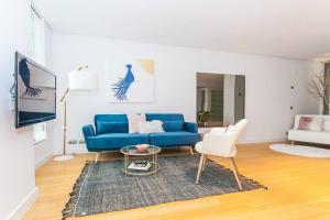 een woonkamer met een blauwe bank en een tafel bij Atocha: Precioso con Parking y Piscina at Lavapies in Madrid