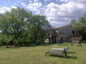 Casale di Pari的住宿－Casa Nati，坐在建筑物前面的草上的一个长凳