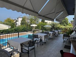 un patio con tavoli, sedie e piscina di Hotel Renata a Lazise