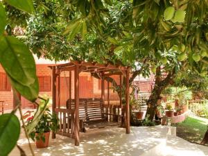 um banco de madeira sob um gazebo num jardim em Pousada Galeria Artes em Bonito