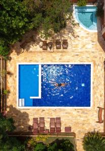 - une piscine avec des chaises et une personne qui s'y baigne dans l'établissement Pousada Galeria Artes, à Bonito