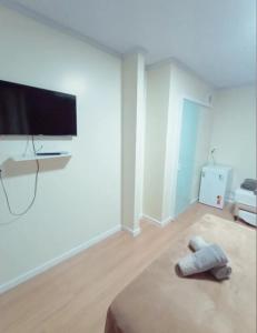 um quarto branco com uma televisão de ecrã plano e uma cama em Pousada Helena em Penha