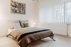 a white bedroom with a large bed with a blanket at Neue Technologie Systemlösungen GmbH in Osterode