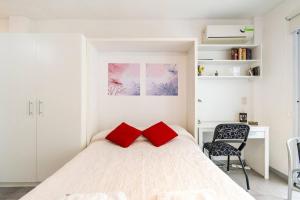Espacio c/ Patio privado, lavadora y TV Premium في بوينس آيرس: غرفة نوم بسرير أبيض ومخدتين حمراء
