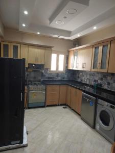 uma cozinha com armários de madeira e uma máquina de lavar e secar roupa em شقه فندقية رائعة في مركز مدينة الإسكندرية em Alexandria