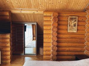 Habitación con pared de madera, cama y espejo. en Сонячний Лаз, en Polyana