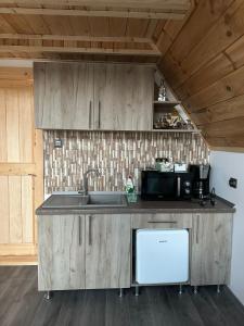 una cocina con armarios de madera y fregadero en La Poalele Vulcanilor, en Densuş