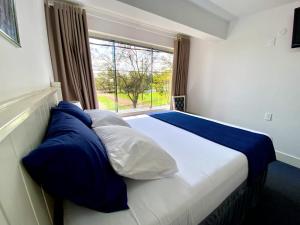 a bed with blue and white pillows and a window at Hotel Renty Beach in Encarnación