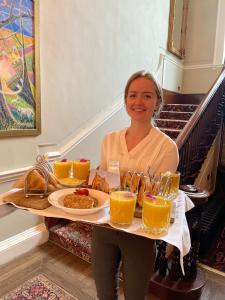 una mujer sosteniendo una bandeja de comida y bebida en Peterstone Court Country House Restaurant & Spa, en Brecon