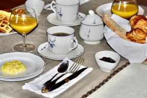 einen Tisch mit Tassen und Teller mit Speisen und Getränken in der Unterkunft Maison d'Hôte du Chateau de Fontariol in Le Theil