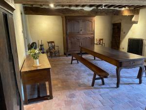 a dining room with a wooden table and benches at Maison d'Hôte du Chateau de Fontariol in Le Theil