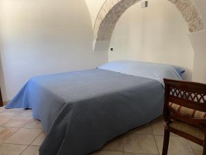 a bedroom with a bed with a blue bedspread at Trullo Ronzicchio in Cisternino