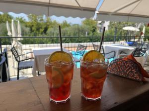 two cocktails sitting on a wooden table on a patio at Hotel Renata in Lazise