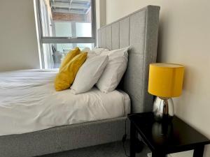 een bed met witte kussens en een gele lamp op een tafel bij Pass the Keys Central Watford Apartment Sleeps 5 with Parking in Watford