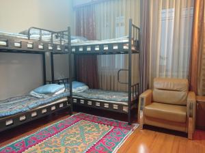 a bedroom with two bunk beds and a chair at KGB Home Hostel in Bishkek