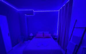 um quarto azul com uma cama num quarto com luzes em Guest Room avec SDB privée près de Paris, Roissy CDG et du village Olympique em Persan