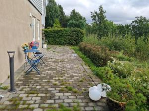 a patio with a table and chairs in a garden at Kaldvell Apartman in Lillesand