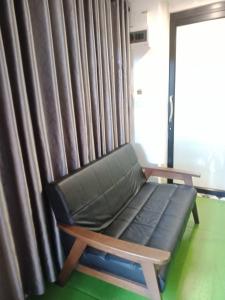 a couch sitting in front of a window with curtains at Kipbox Hotel Trang in Trang