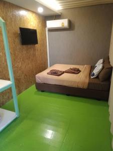 een slaapkamer met een bed en een groene vloer bij Kipbox Hotel Trang in Trang