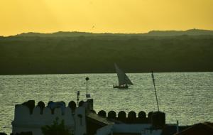 a sail boat in the water at sunset at JamboHouse Lamu in Lamu