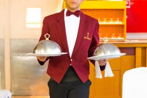 a man in a red suit holding two silver dishes at Hotel Principe in Bibione +61 photos